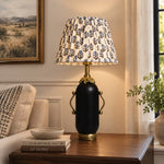 Charger l'image dans la visionneuse de la galerie, Matte black floral table lamp glowing on a dark side table