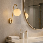 Cargar imagen en el visor de la Galería, Brass globe wall light used beside a bathroom vanity mirror