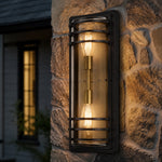 Załaduj obraz do przeglądarki galerii, Large bronze glass outdoor wall sconce glowing on a stone wall