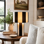 Carica l'immagine nella visualizzazione Galleria, Black and white striped woven table lamp lit on a wood side table