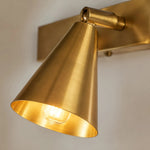 Bild in die Galerieansicht laden, Close detail of lit brass cone shade and wall bracket