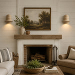Załaduj obraz do przeglądarki galerii, Pair of travertine wall sconces installed beside framed art above a living room fireplace