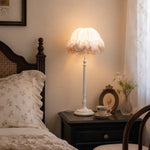 Afbeelding laden in galerijweergave, Ruffled table lamp glowing on a dark wood nightstand beside a vintage bed