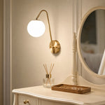 Cargar imagen en el visor de la Galería, Brass globe wall light near a vanity and table setting