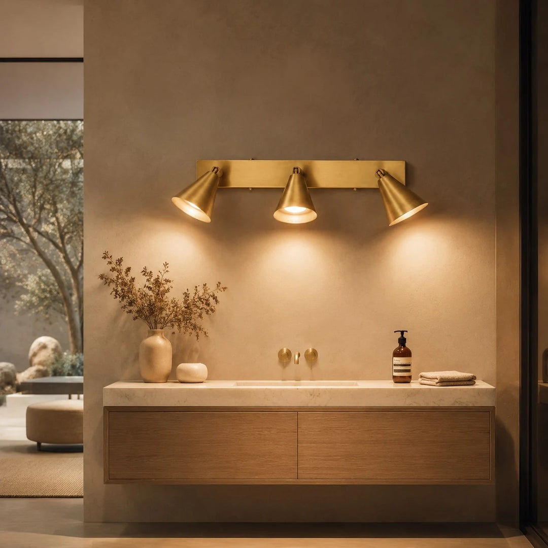 Brass three-head adjustable wall light over a bathroom vanity