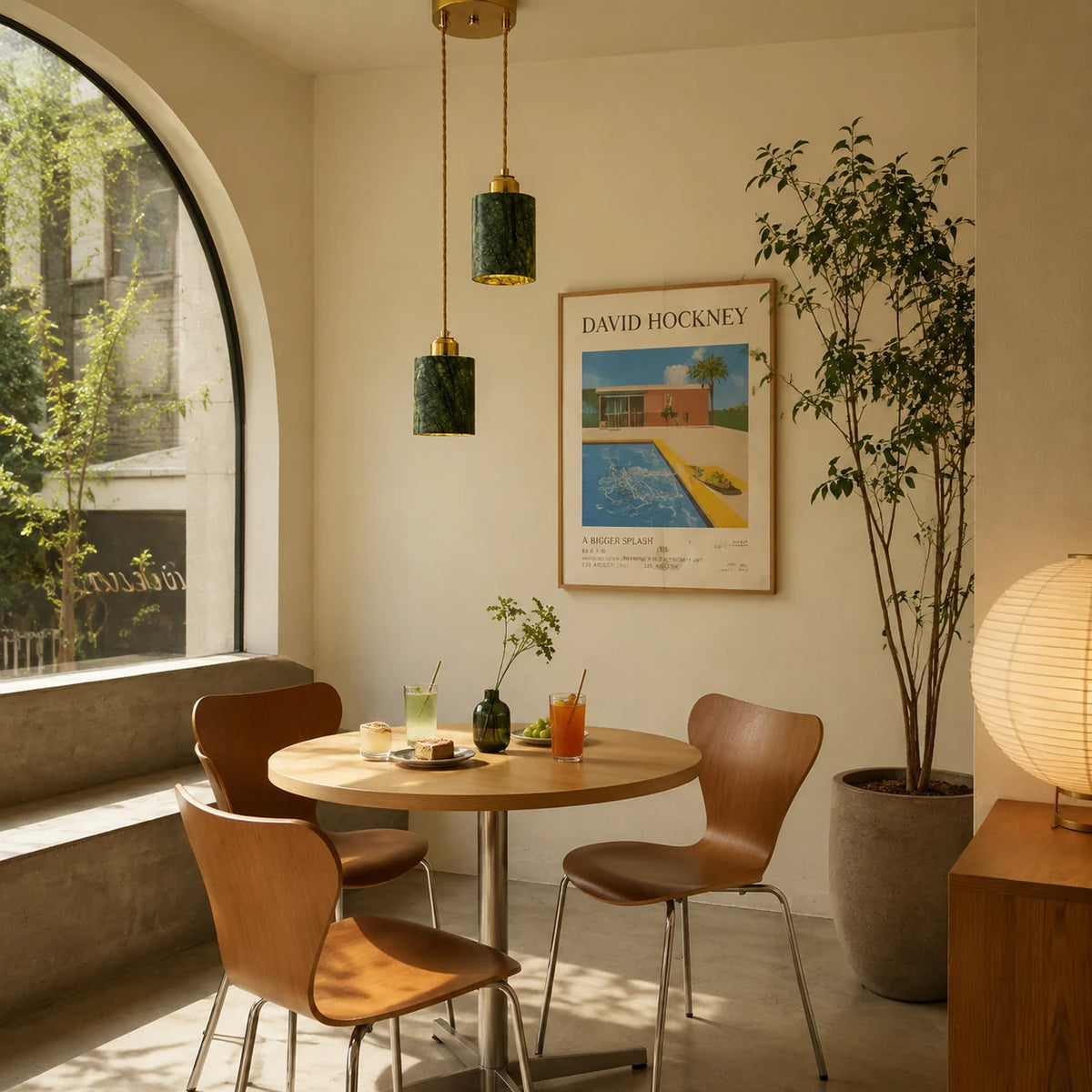 Two green jade cylinder pendant lights installed above a small dining table by an arched window