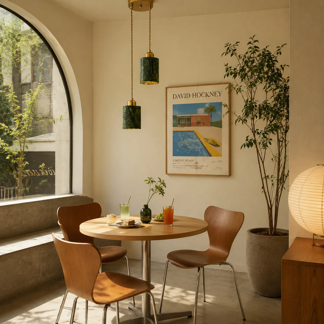 Two green jade cylinder pendant lights installed above a small dining table by an arched window