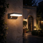 Load image into Gallery viewer, Black outdoor wall lamp installed beside an entry at night