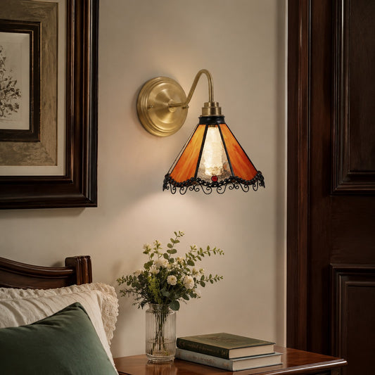 Orange stained glass wall sconce beside a vanity mirror