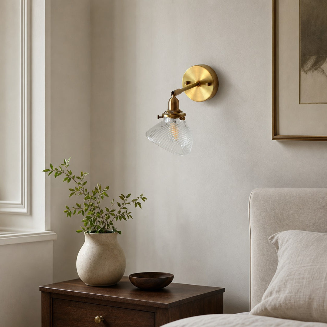 Clear glass wall lamp installed beside a bed