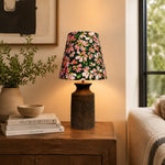Bild in die Galerieansicht laden, Floral ceramic table lamp glowing beside a sofa on a wooden side table