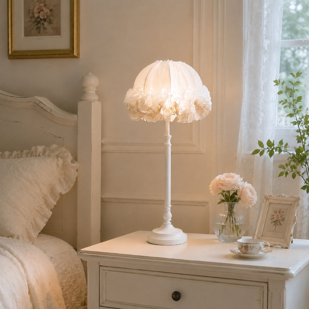 Ruffled table lamp glowing on a white bedside dresser in a bright bedroom