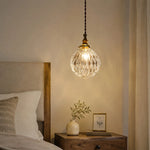 Cargar imagen en el visor de la Galería, ribbed clear glass pendant light glowing over a bedside nightstand