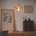 Cargar imagen en el visor de la Galería, Hand carved wood pendant light casting warm light on a quiet wall