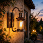 Cargar imagen en el visor de la Galería, Antique bronze wall lantern glowing on an outdoor entry wall