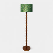 Full view of sculptural wood floor lamp with patterned fabric drum shade