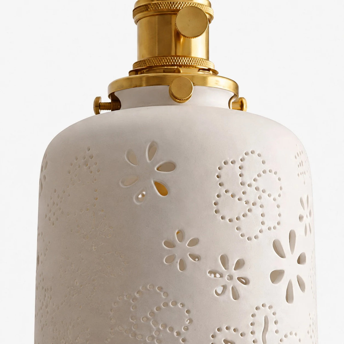 Close view of white ceramic shade with cutout floral pattern