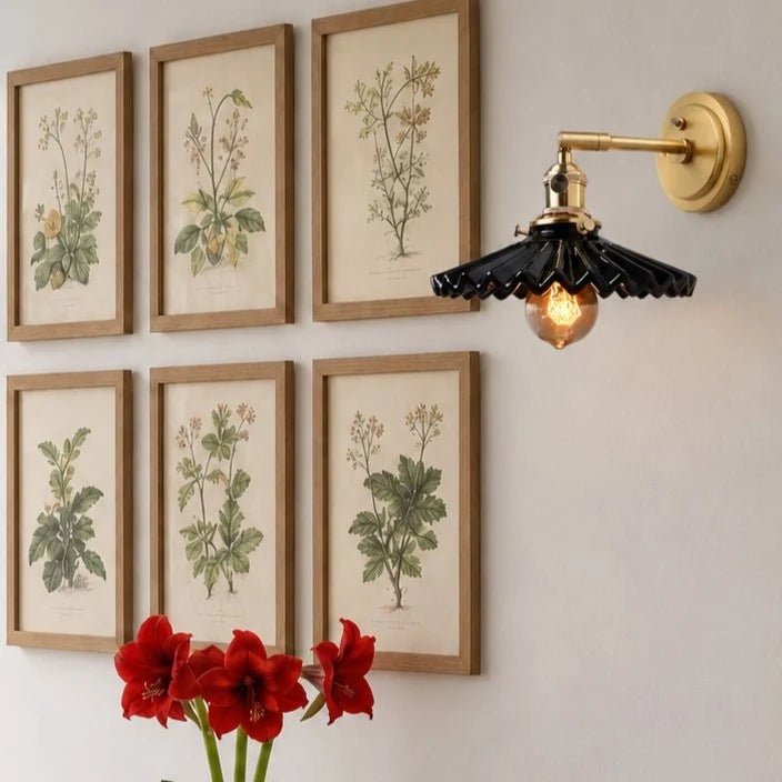 Black wall sconce above framed botanical art
