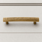 Afbeelding laden in galerijweergave, Hammered brass cabinet pull on white cabinet drawer