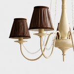 Load image into Gallery viewer, Close-up of cream iron chandelier body with curved arms and bead trim