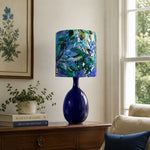 Afbeelding laden in galerijweergave, Green botanical fabric ceramic table lamp styled by a sofa