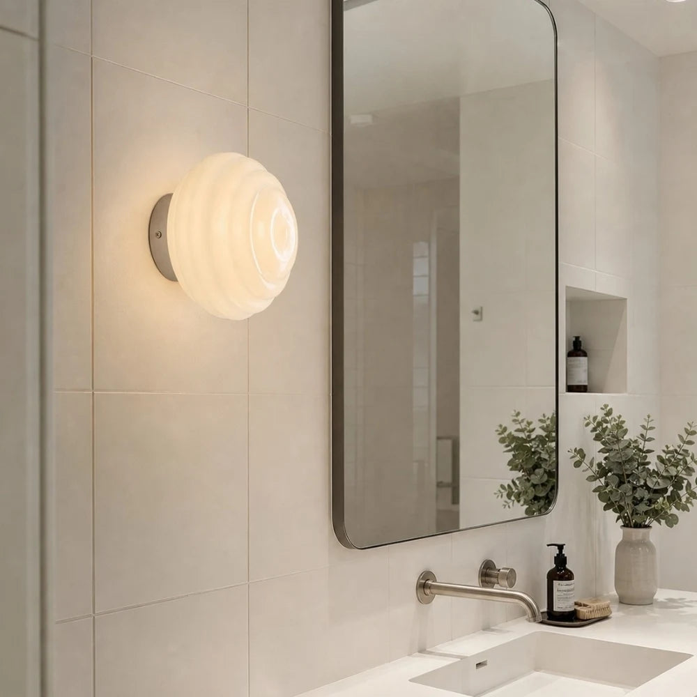 Cream ribbed glass wall sconce near a bathroom vanity