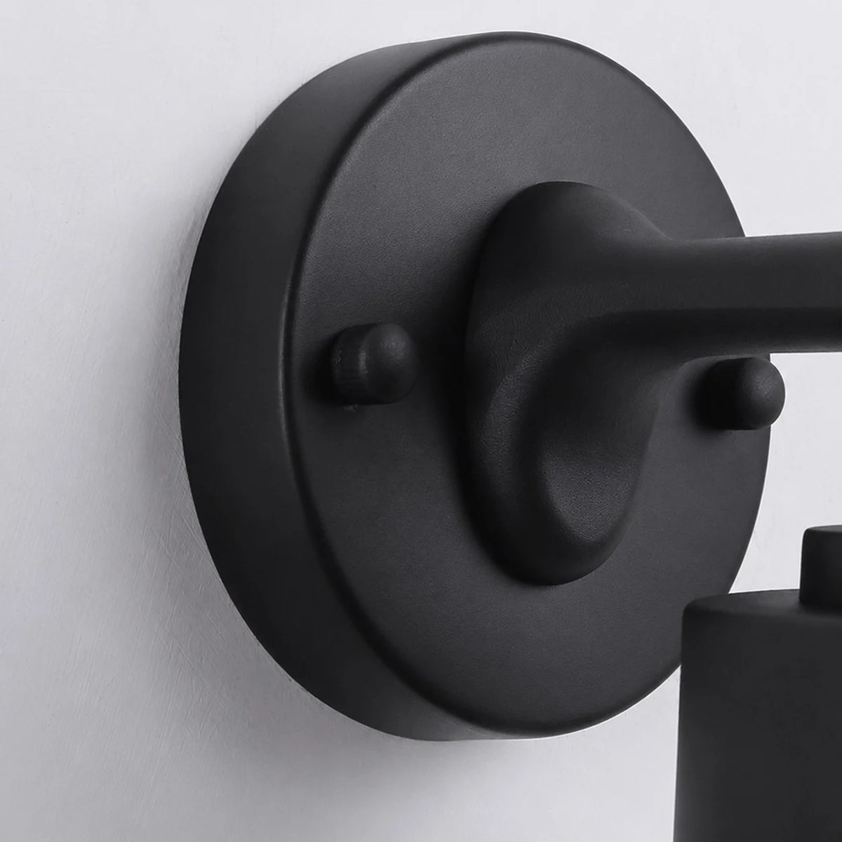 Close view of the black round wall plate and metal arm