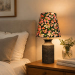 Bild in die Galerieansicht laden, Floral ceramic bedside lamp glowing on a nightstand in a warm bedroom