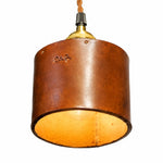 Cargar imagen en el visor de la Galería, Close-up of brown leather cylinder shade with warm inner glow