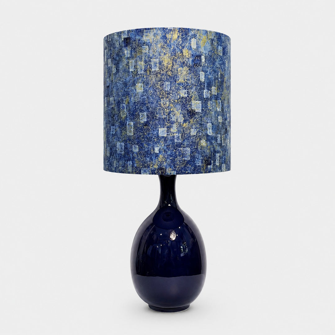 Blue gold patterned fabric ceramic table lamp on plain background