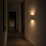 Carica l'immagine nella visualizzazione Galleria, Chrome wall sconce casting warm light in a quiet hallway