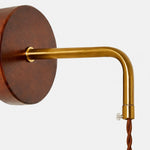 Cargar imagen en el visor de la Galería, Close view of the round wooden wall plate and brass arm connection on the bedside wall lamp
