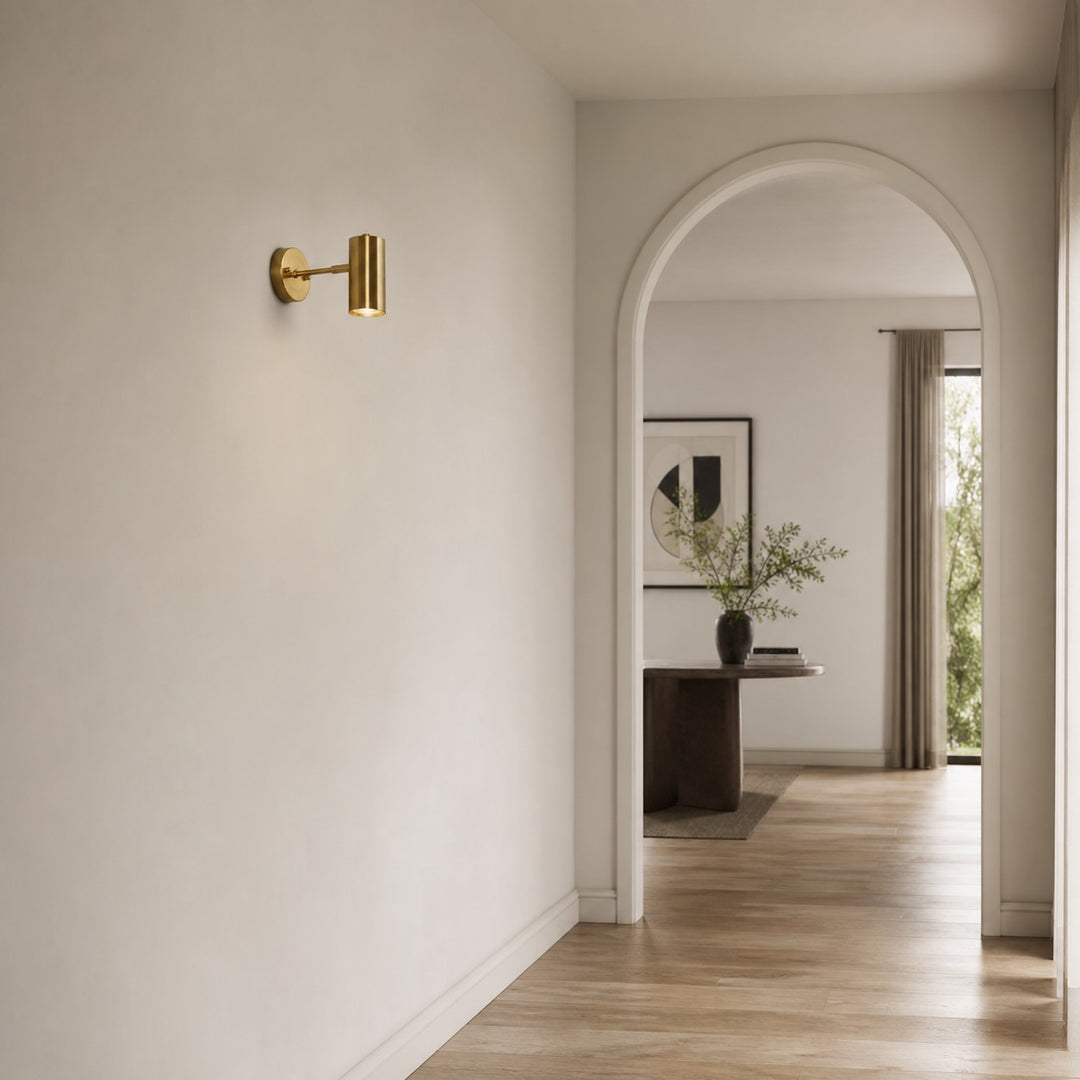 Brass cylinder wall sconce in a bright hallway