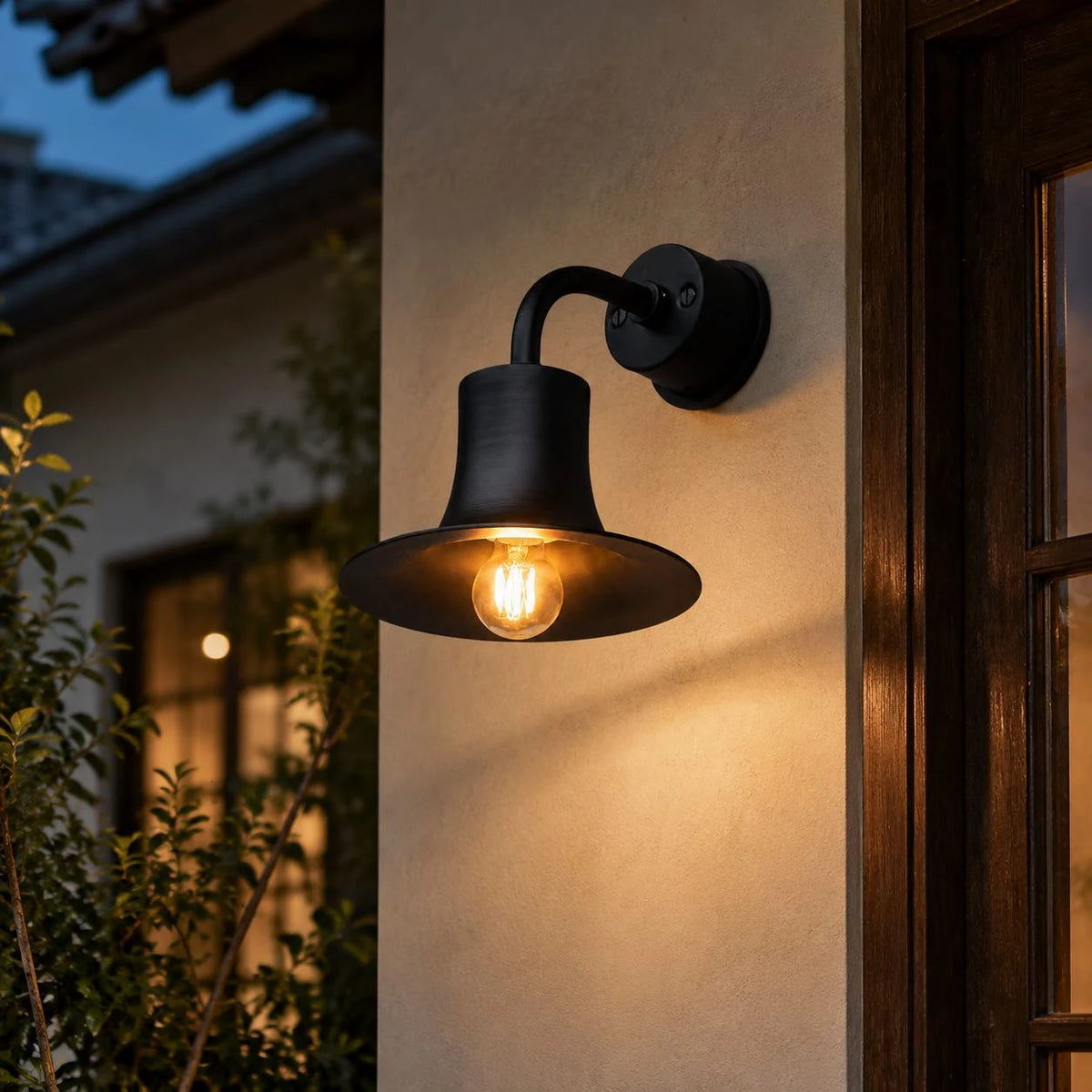 Black wall sconce lighting an exterior wall beside a window