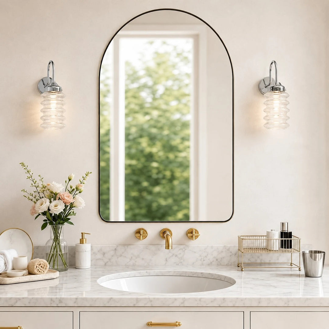 Pair of chrome ribbed glass wall sconces around an arched bathroom mirror