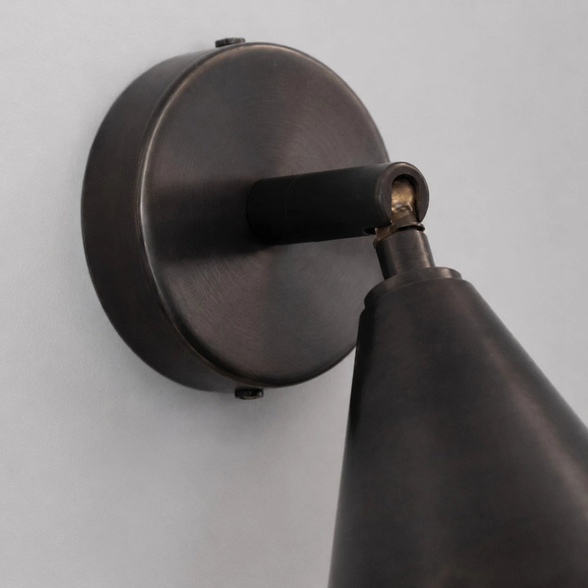 Round wall plate and adjustable arm detail on matte black wall light