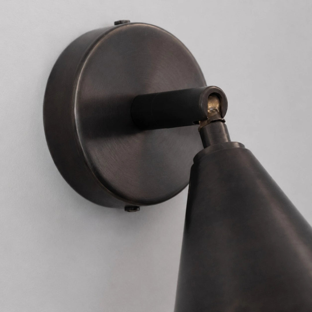 Round wall plate and adjustable arm detail on matte black wall light