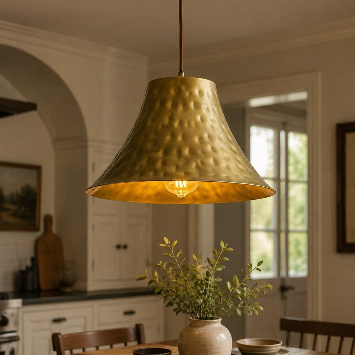 Large hammered brass pendant light above a kitchen table