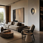 Afbeelding laden in galerijweergave, Black sculptural disc wall sconce in a modern living room