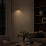 Carica l'immagine nella visualizzazione Galleria, Brass cylinder wall sconce casting downward light in a quiet evening living room