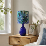 Afbeelding laden in galerijweergave, Green botanical fabric ceramic table lamp in a bedroom setting