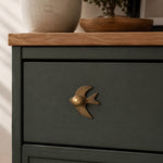 Afbeelding laden in galerijweergave, Antique brass swallow cabinet knob on a dark green drawer